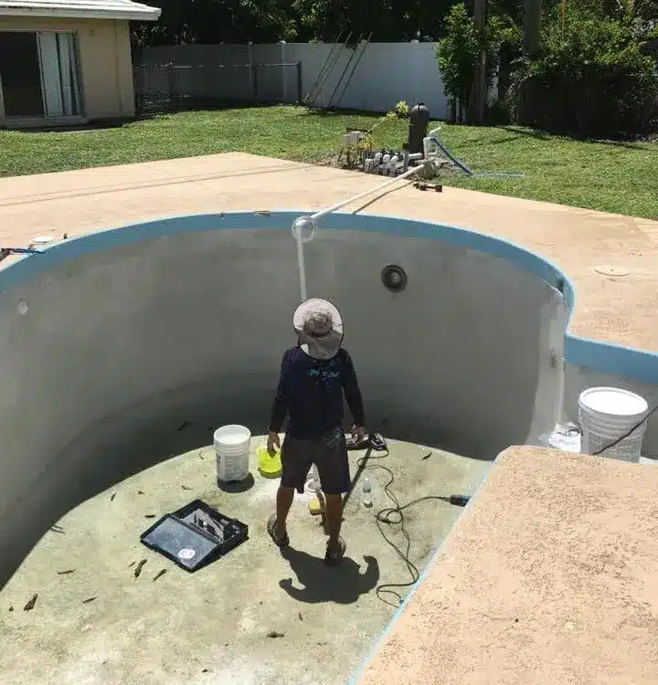 A pool technician fixing a leak with a bucket and hose.