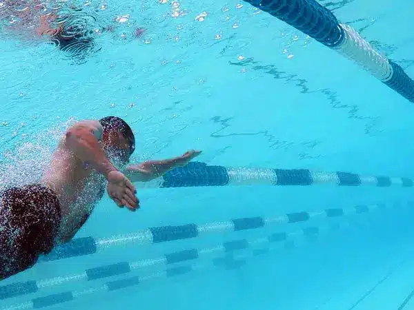 A man enjoying the pool with his hands in the air.